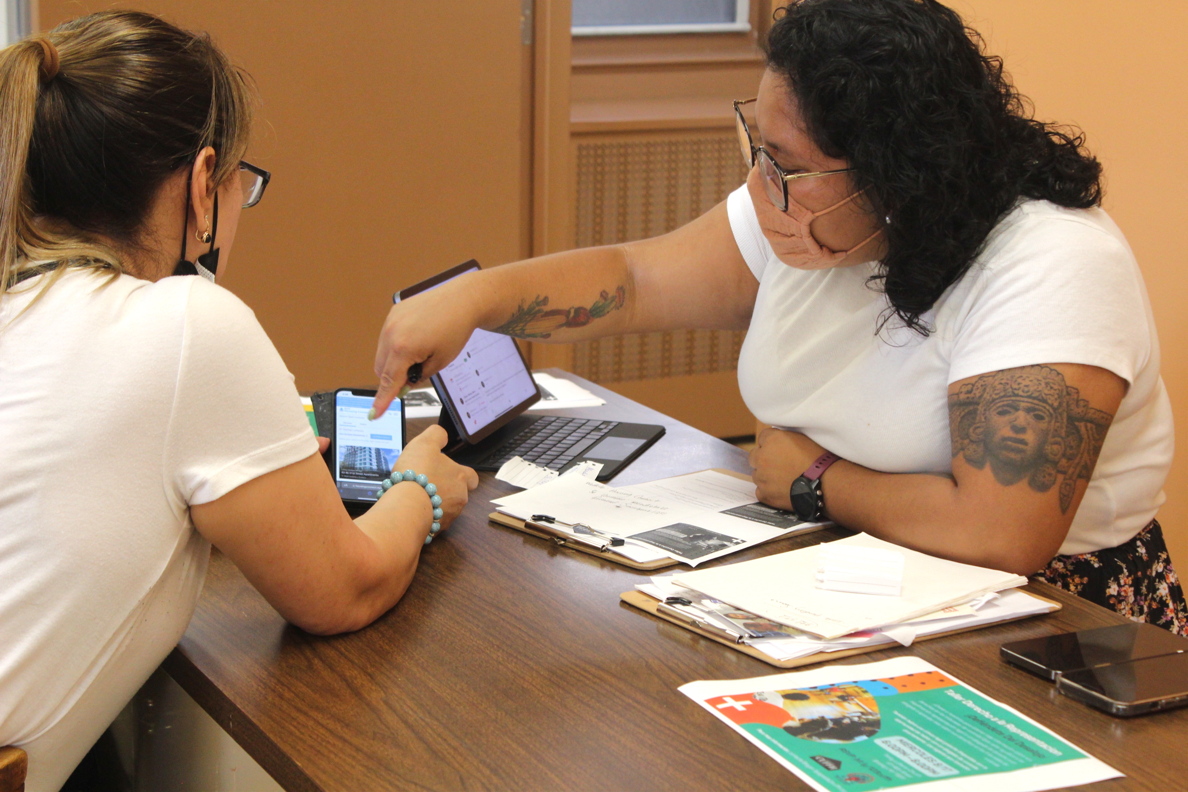 CUFFH Constituent Services Specialist helps community member with application for affordable housing. The CUFFH staff member is pointing to a screen. CUFFH Constituent Services Specialist helps community member with application for affordable housing. The CUFFH staff member is pointing to a screen.
