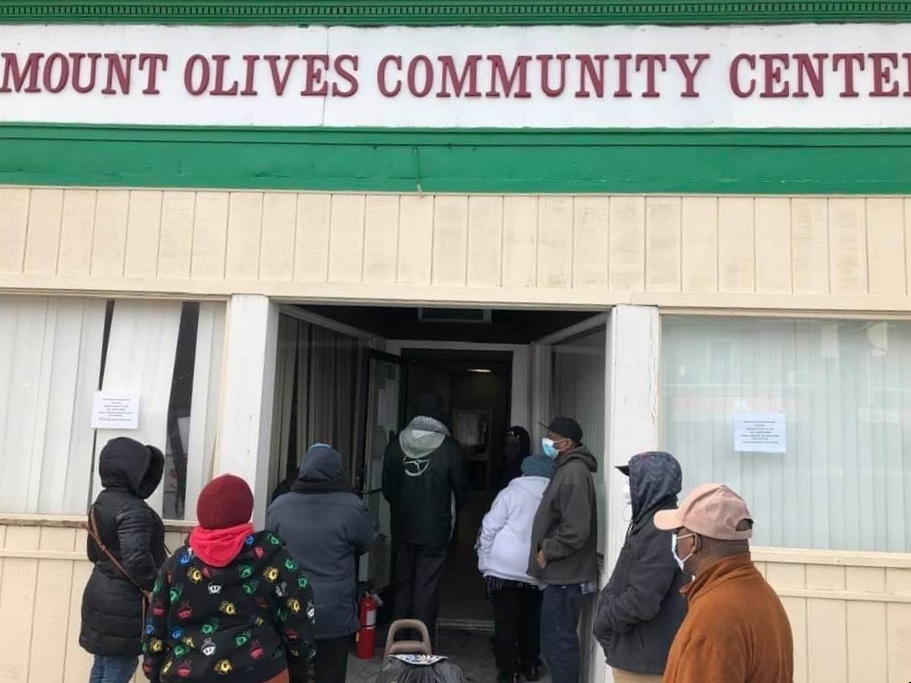 People enter a building under a sign reading "Mount Olives Community Center"