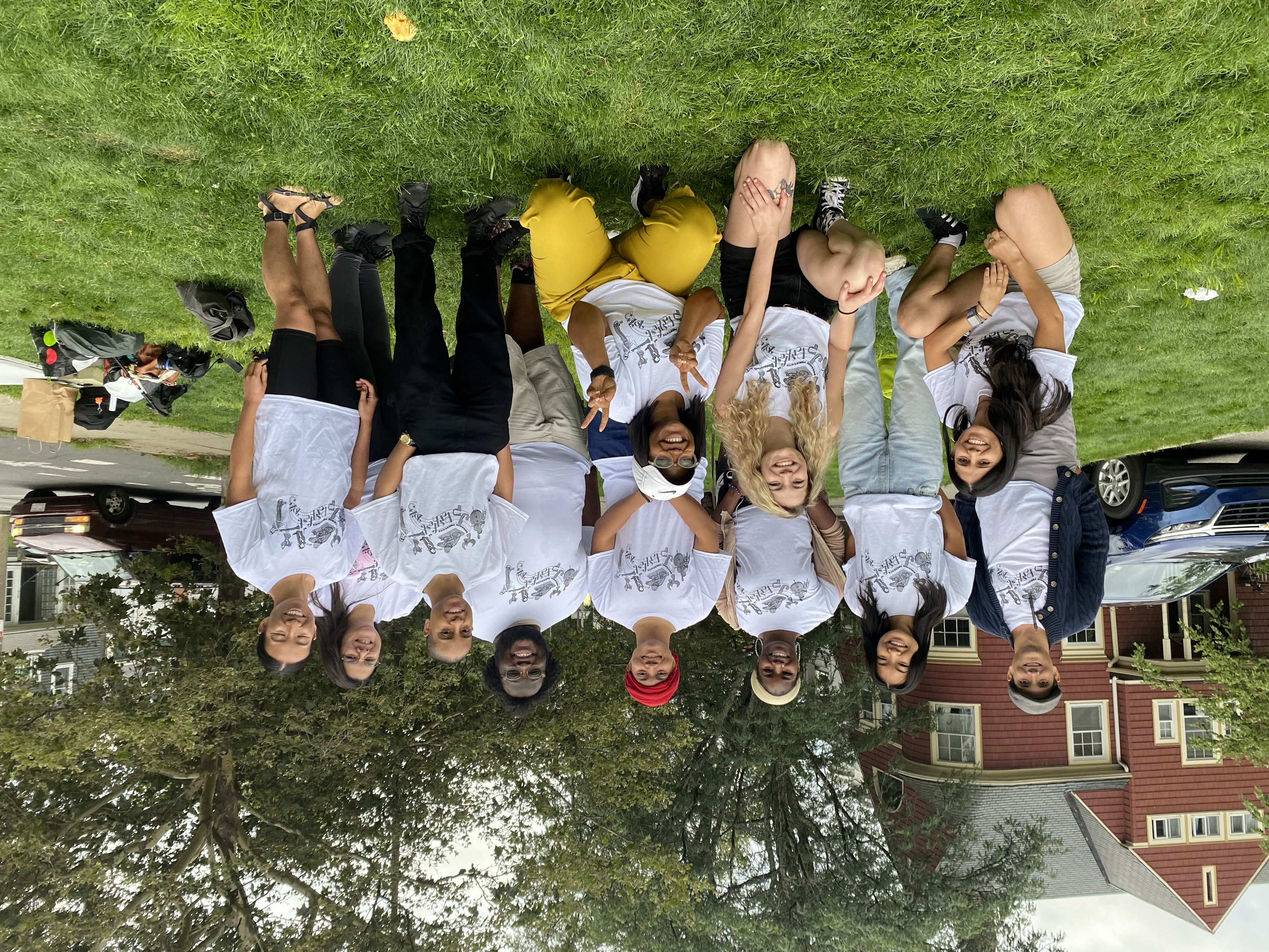 A photo of a group of people all wearing white t-shirts, smiling at an outdoor community event A photo of a group of people all wearing white t-shirts, smiling at an outdoor community event