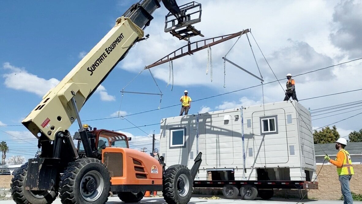 A crane lifts a plastic modular home onto the asphalt A crane lifts a plastic modular home onto the asphalt