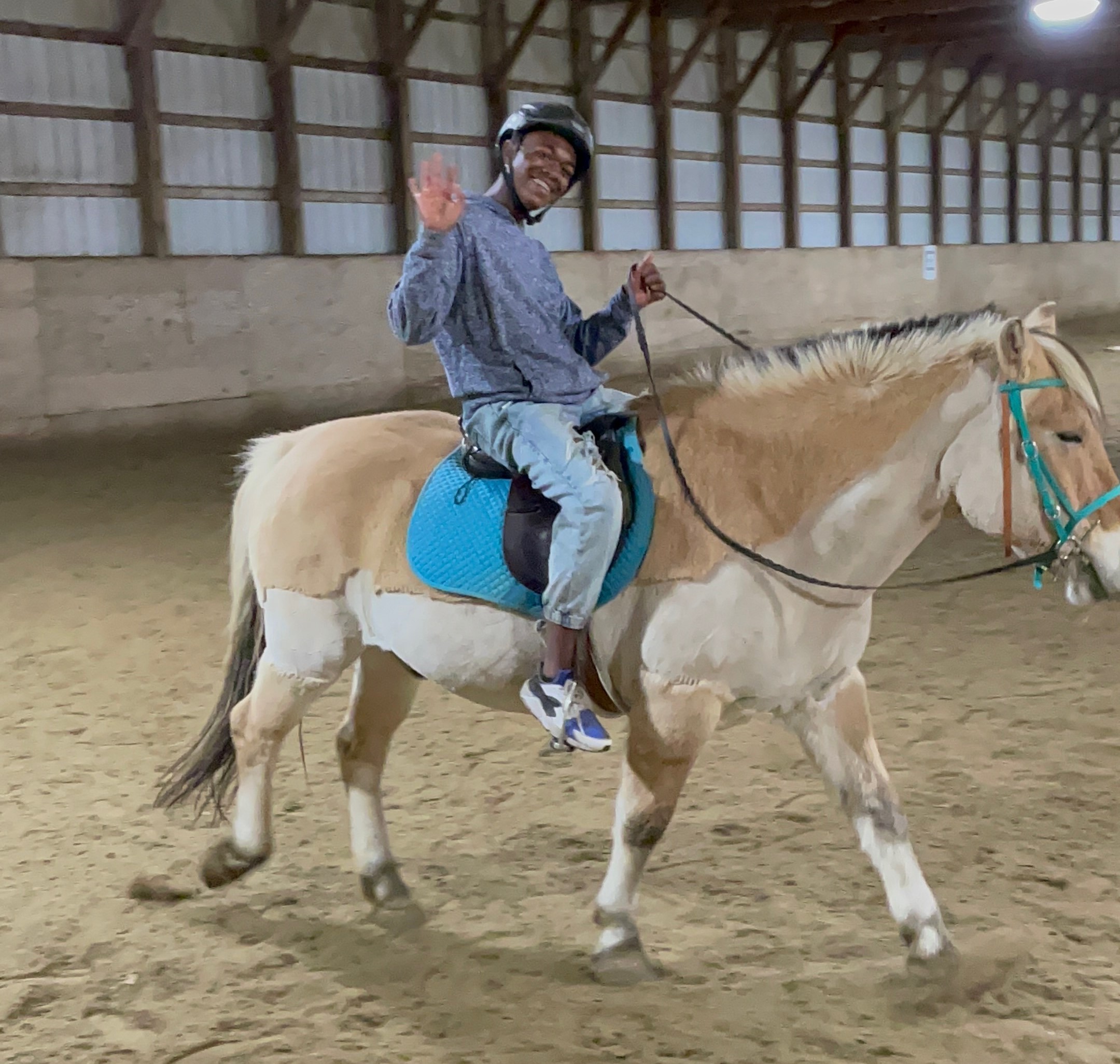 A young person rides a tan and grey horse on a dirt field. A young person rides a tan and grey horse on a dirt field.