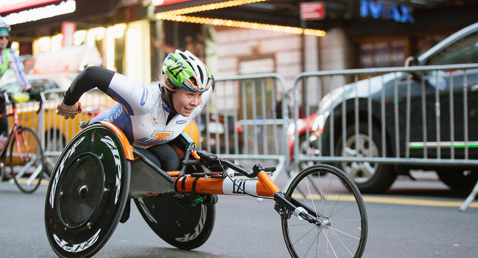 Woman in competition gear propelling herself in racing wheelchair Woman in competition gear propelling herself in racing wheelchair