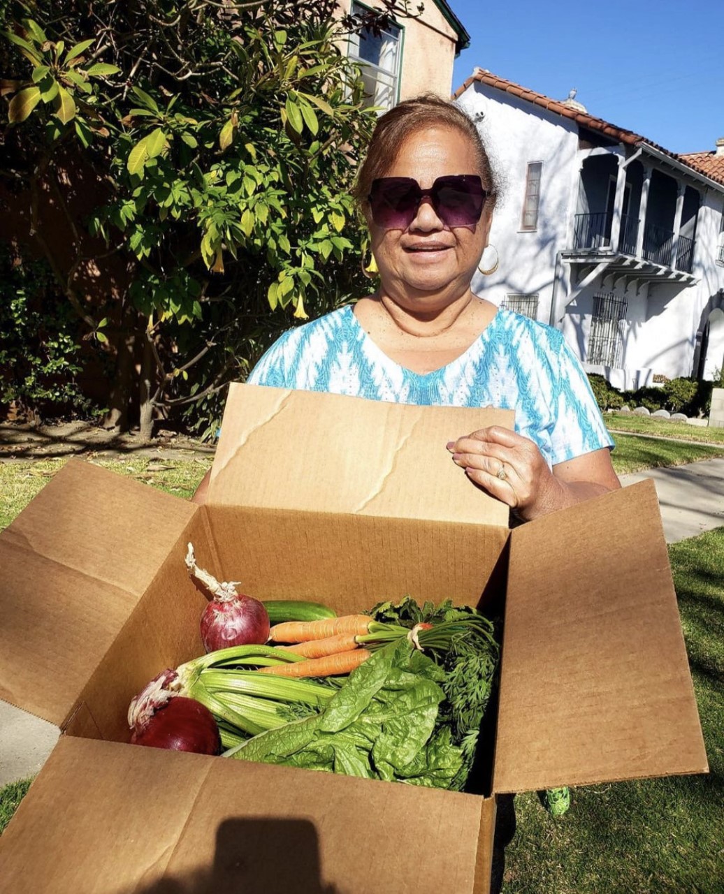 A Feed Black Futures member with a box of produce