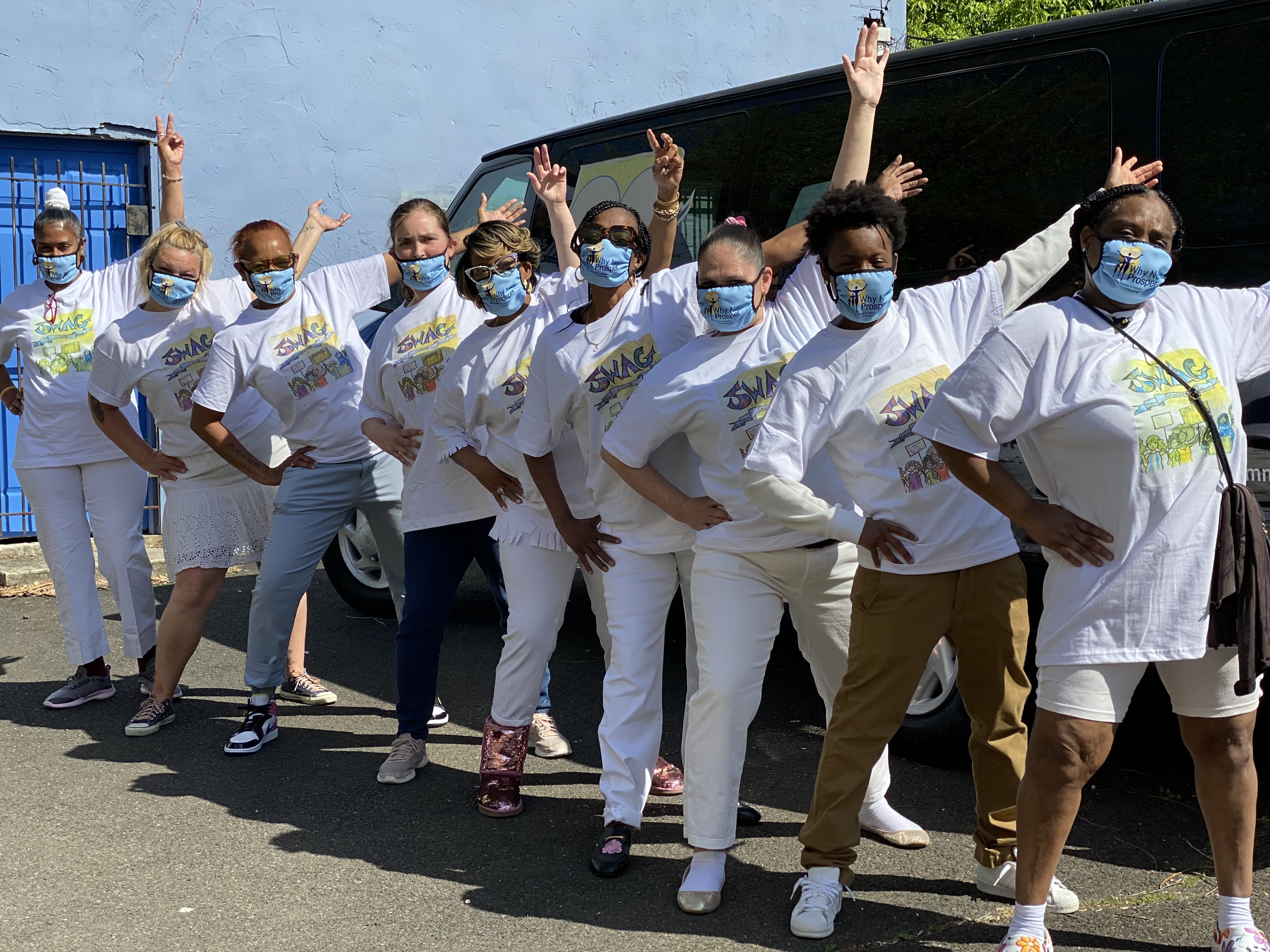 9 women in matching white "swag" t-shirts pose next to a van 9 women in matching white "swag" t-shirts pose next to a van