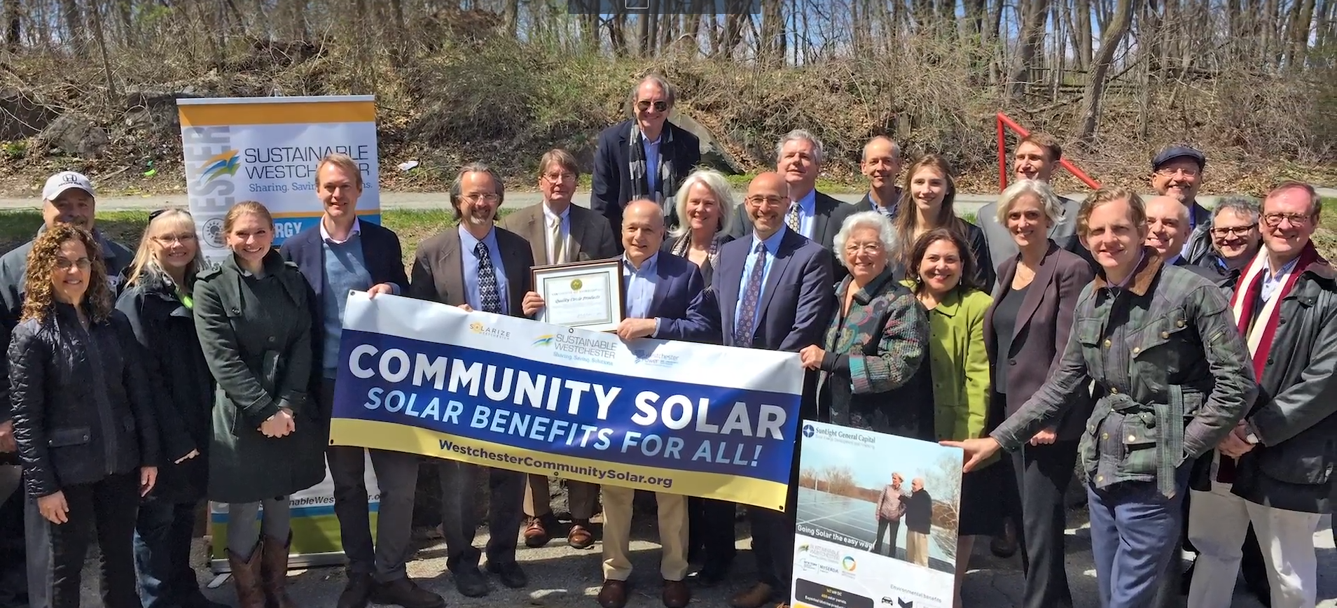 A group of people pose for a group photo with a sign that says "Community Solar Solar Benefits for All!" A group of people pose for a group photo with a sign that says "Community Solar Solar Benefits for All!"