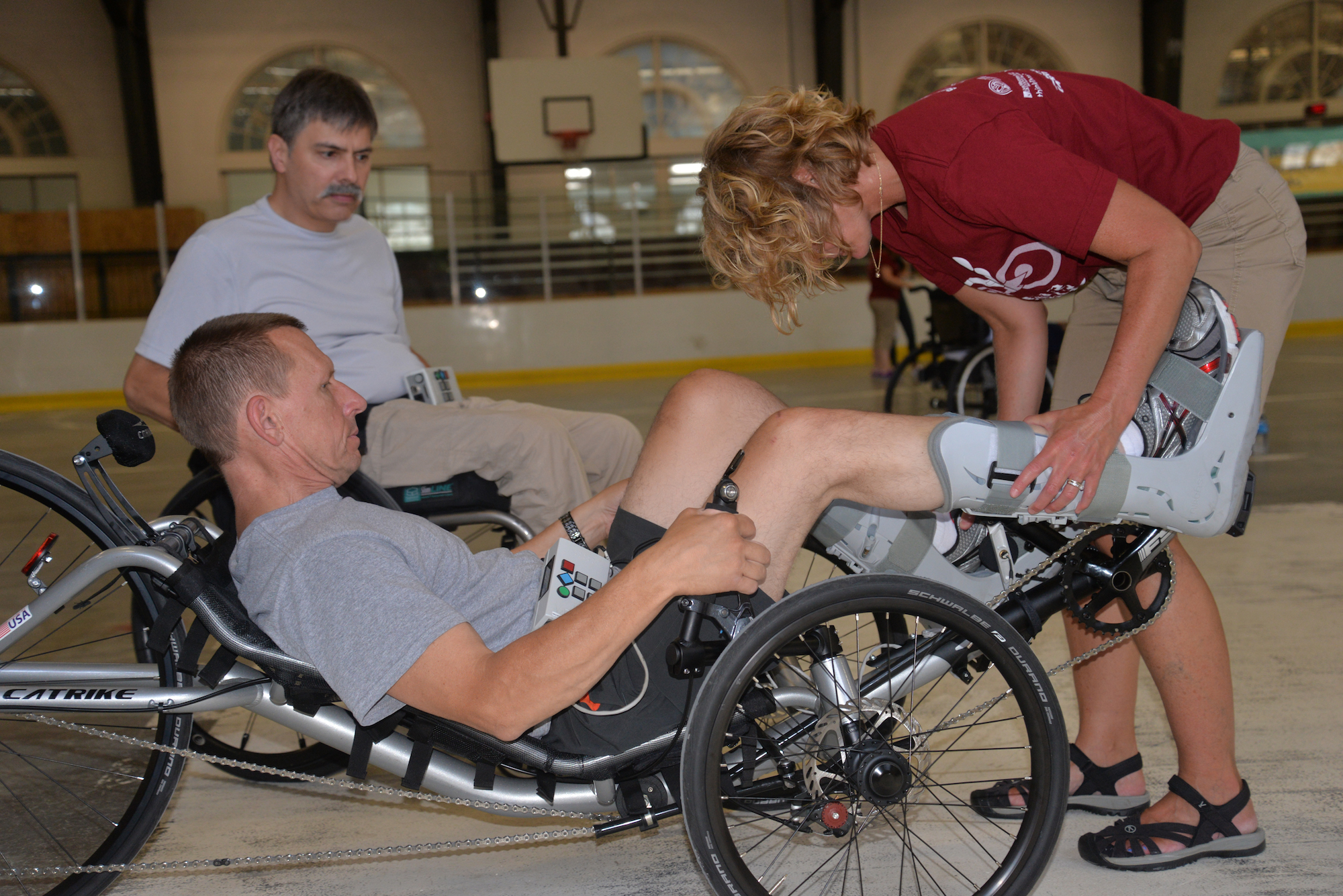 Woman adjusting man’s foot in adaptive bike Woman adjusting man’s foot in adaptive bike