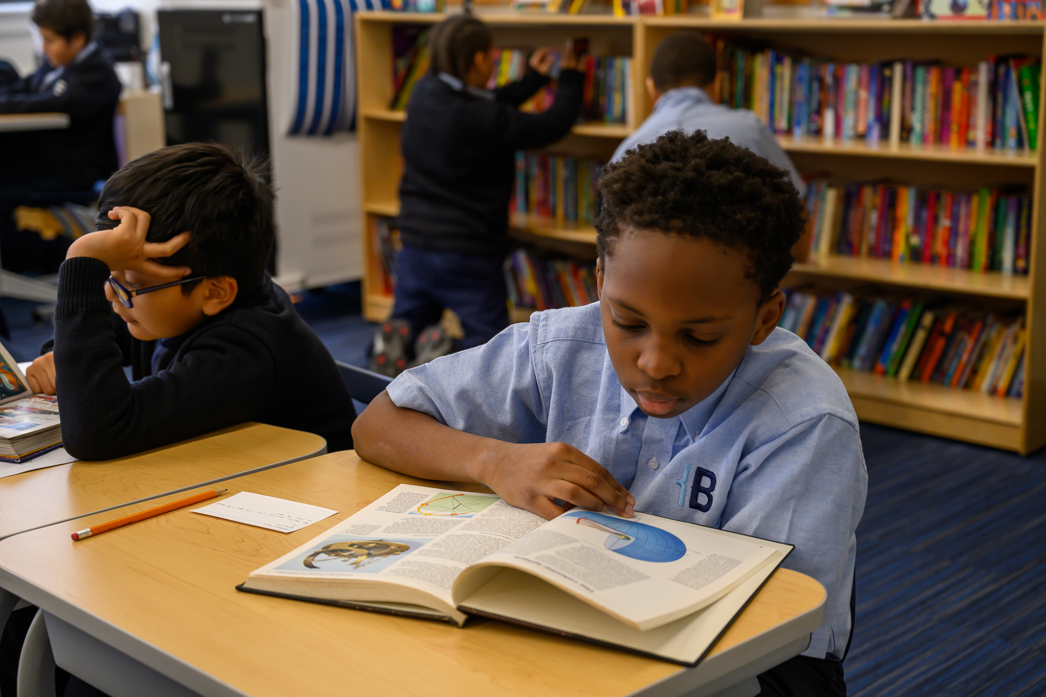 Two students read at their desks.