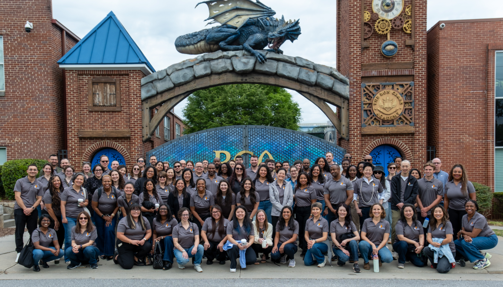 NFF staff lined up for a photo in front of the entrance to RCA, which has large brick columns and a blue tile gate with a dragon sculpture on top.